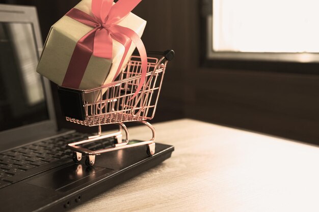 사진 테이블 위 에 있는 노트북 에 있는 장난감 쇼핑 카트 에 있는 선물 상자 의 클로즈업