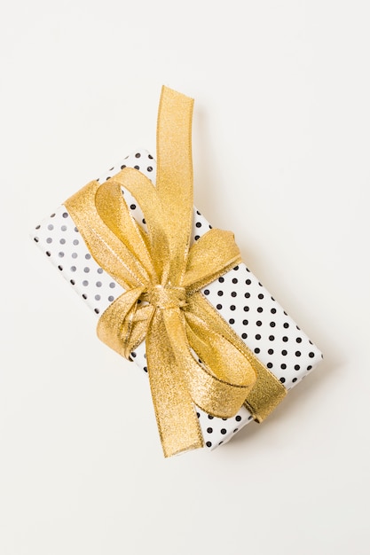 Крупный план подарка, завернутые в пунктирную бумагу, украшенную золотой лентой, изолированных на белом фоне
