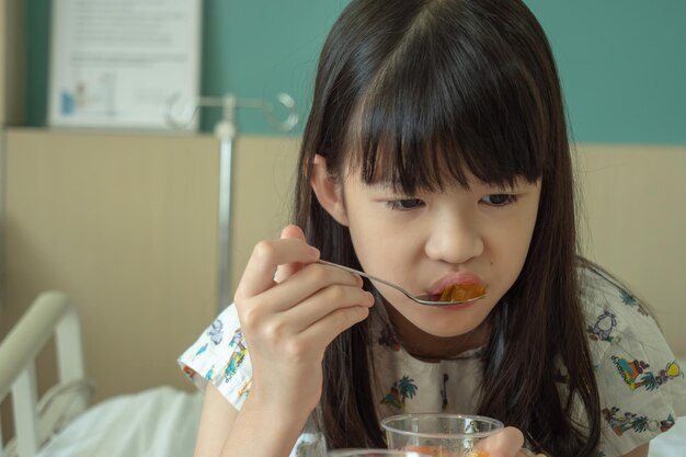 写真 病院のベッドに座って食べ物を食べている女の子のクローズアップ