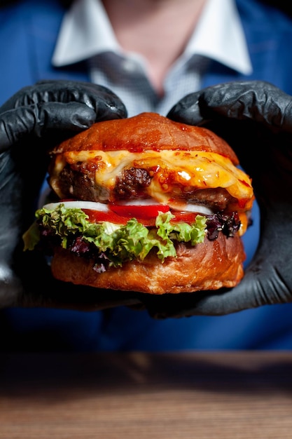Фото Клоуз-ап с рукой, держащей бургер на столе