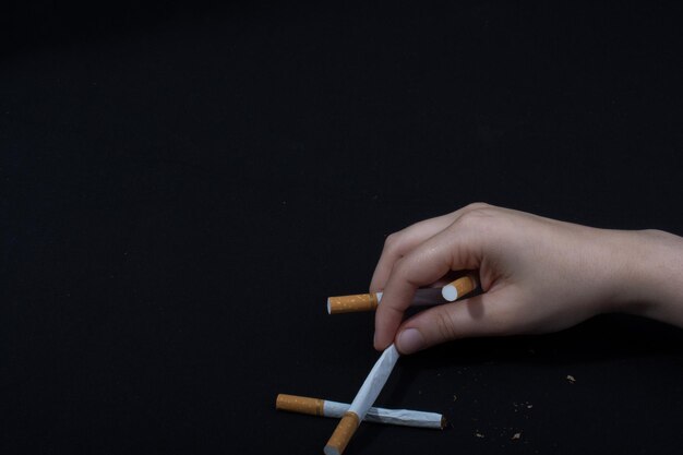 Фото Клоуз-ап руки, держащей сигареты на черном фоне