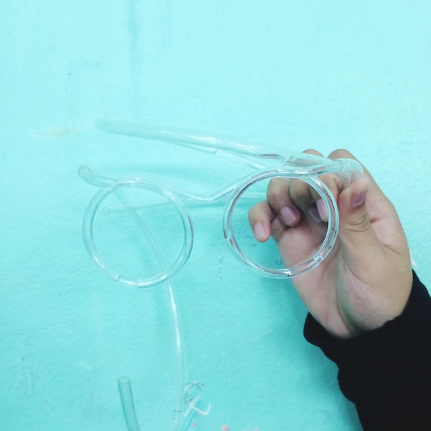 Фото Клоуз-ап руки, держащей соломинку против бирюзовой стены