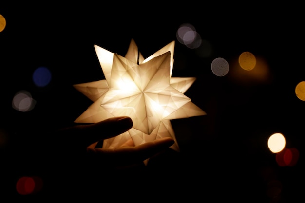 Фото Клоуз-ап руки, держащей освещенную декорацию ночью