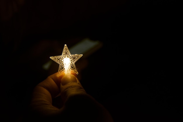 Фото Клоуз-ап руки, держащей освещенную звезду на черном фоне
