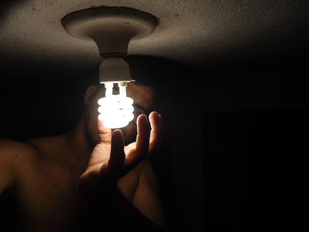 Фото Клоуз-ап руки, держащей лампочку у стены