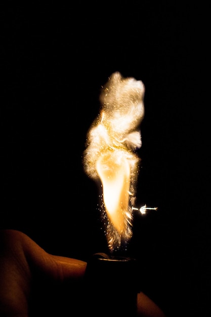 Фото Клоуз-ап руки, держащей зажигатель на черном фоне