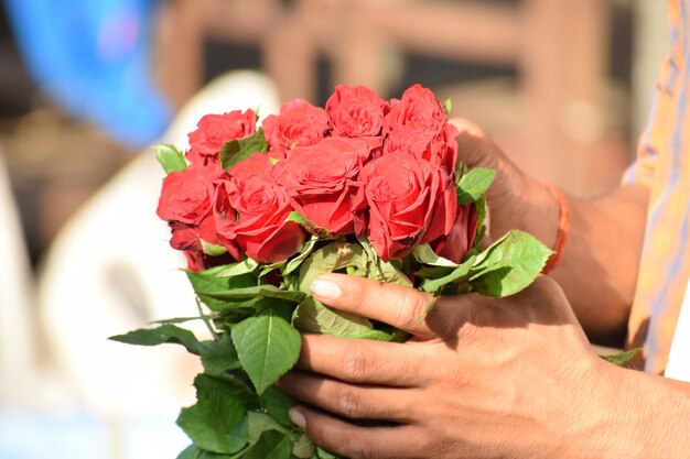 写真 バラの花束を握っている手のクローズアップ.