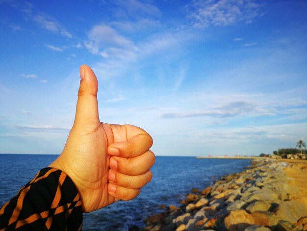 Фото Клоуз-ап руки, держащей море на фоне неба
