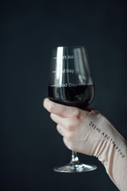 Фото Клоуз-ап руки, держащей бокалы с вином на черном фоне