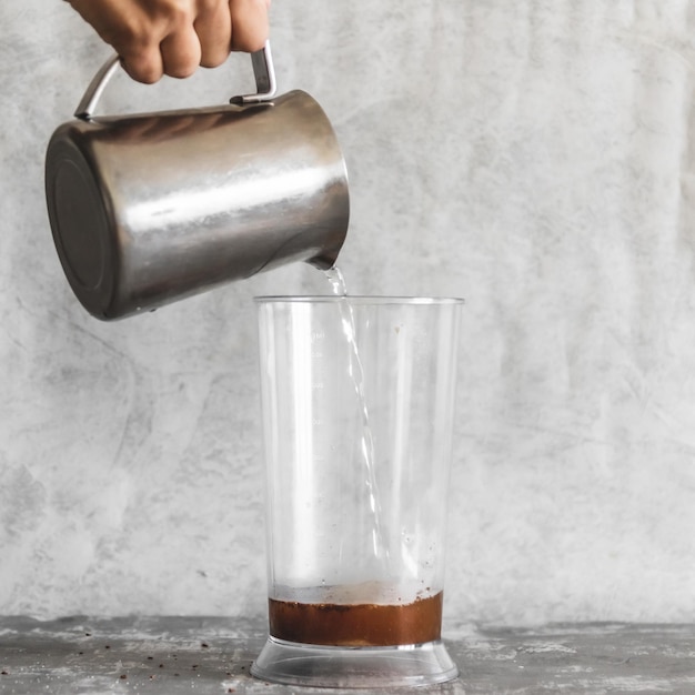 사진 컵 에 있는 인스턴트 커피 에 물 을 부는 손 의 클로즈업