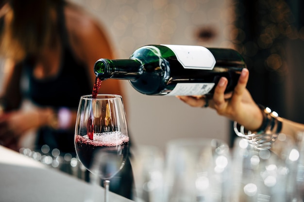Фото Клоуз-ап руки, наливающей вино в стакан