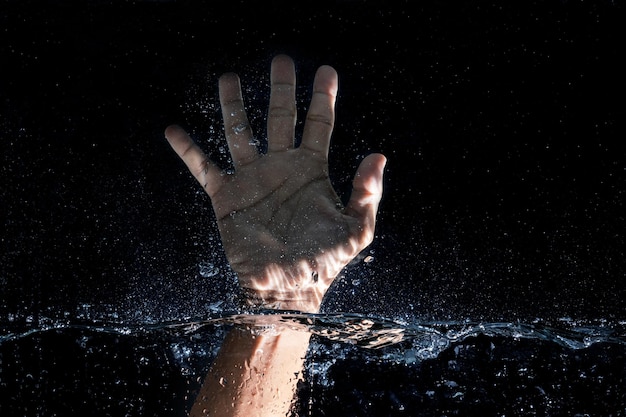 写真 黒い背景で水に触れる手のクローズアップ