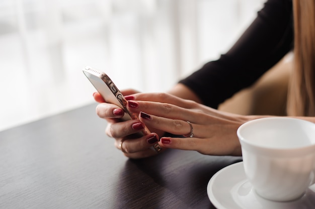 写真 レストラン、カフェで彼女の携帯電話を使用して手の女性のクローズアップ