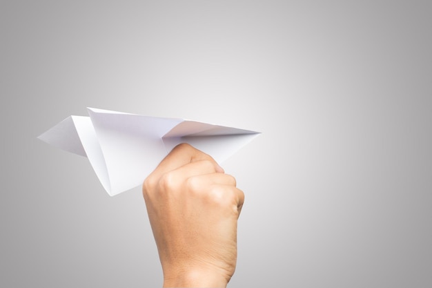 Фото Клоуз-ап человеческой руки, держащей бумажный самолет на сером фоне