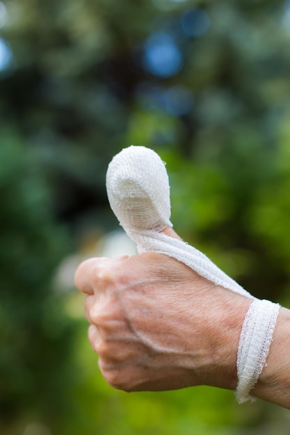 Фото Близкий взгляд на человеческую руку с большим пальцем, обернутым повязкой на открытом воздухе