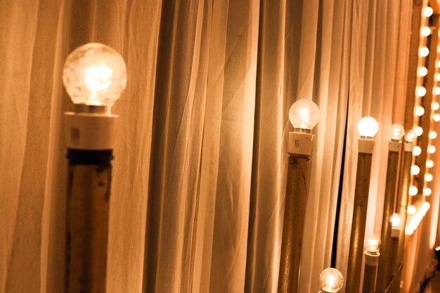 Фото Близкий взгляд на освещенные лампочки на столбах с помощью занавески