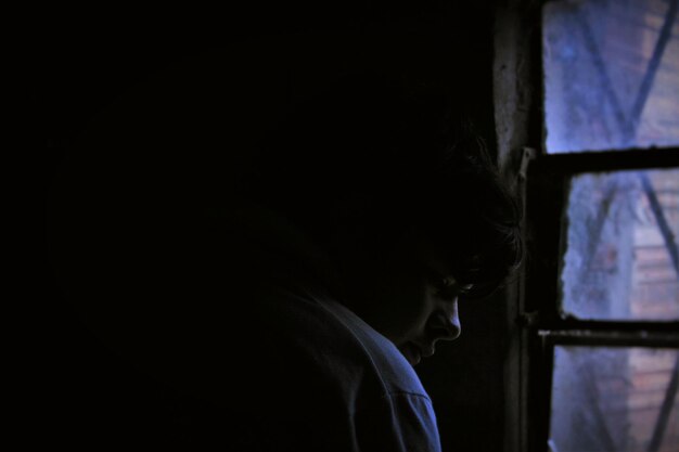 Фото Клоуз-ап человека у окна в темной комнате