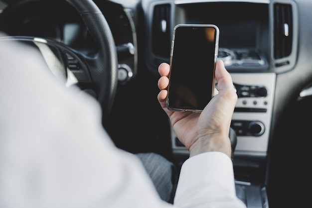 写真 車の中の空のスクリーンで携帯電話を持っている男の手のクローズアップ