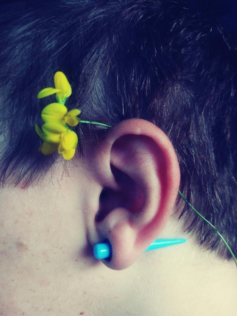 Фото Клоуз-ап человека с цветом на ухе и голубой сережкой