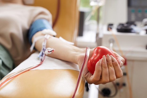 Фото Крупным планом - пациентка с трубками в руке, сжимающая мяч в руке во время сдачи крови