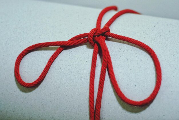 Фото Близкий план красной ленты, привязанной к бумаге