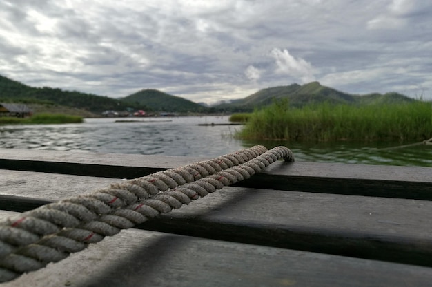 Фото Клоуз-ап веревки на причале в реке на фоне облачного неба