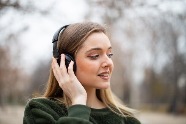 Фото Клоуз-ап улыбающейся женщины, слушающей музыку, в то время как смотрит в другую сторону
