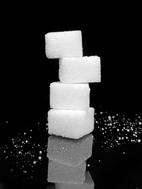 Фото Ближайший план сложенных кубиков сахара на столе на черном фоне