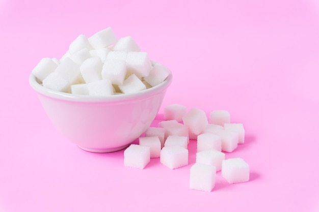 Фото Клоуз-ап кубиков сахара в миске на розовом фоне