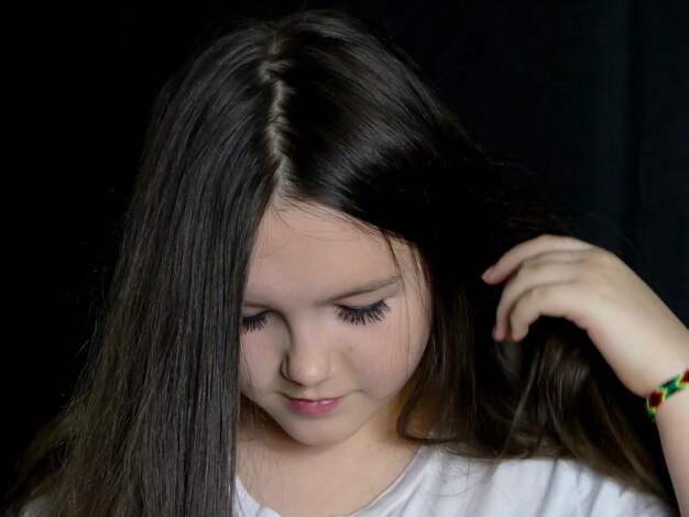 사진 검은 바탕에 긴 검은 머리카락을 가진 십대 소녀의 클로즈업