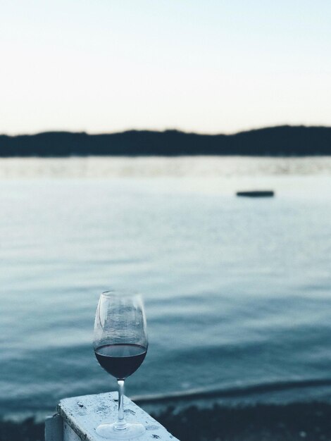 Фото Крупный план винного стакана у озера на фоне ясного неба