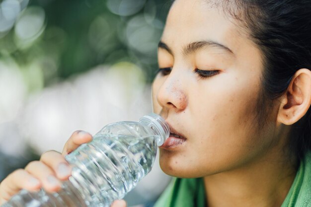 写真 ボトルから水を飲んでいる女性のクローズアップ