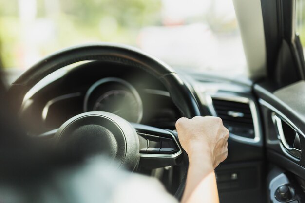 写真 ⁇ 昧な背景でステアリングホイールを握っている女性の運転手の手のクローズアップ