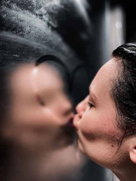 写真 湿ったガラスの上でキスする女性のクローズアップ