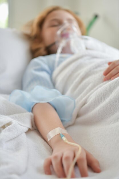 Фото Клоуз-ап женщины, лечащейся внутривенной капельницей, спящей на больничной постели