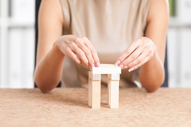 写真 白いオフィスの職場で木のレンガで遊ぶ女性の手の接写。休憩の概念