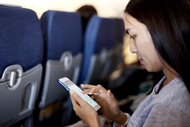 写真 飛行機で旅行している間 ⁇ 電話を使っている女性のクローズアップ