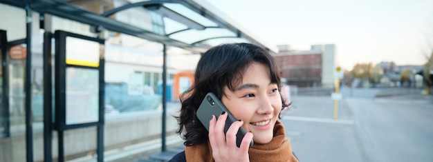 写真 携帯電話で話すアジアの若い女性の接写は、電話でバスを待ちながら会話をしています