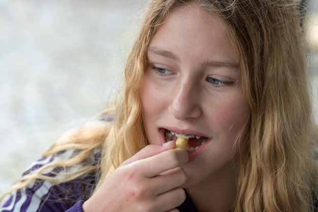 写真 カシューナッツを食べている若い女性のクローズアップ