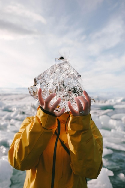 写真 海に逆らって氷を握っている若い女性のクローズアップ