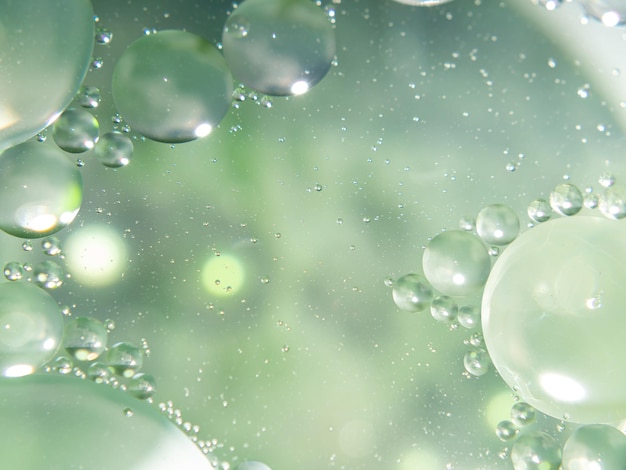 A close up of oil drops in a green and Blurred background