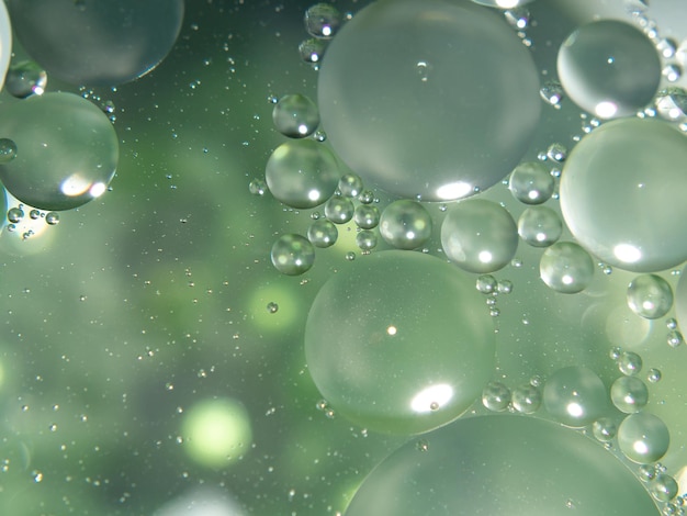 A close up of oil drops in a green and Blurred background