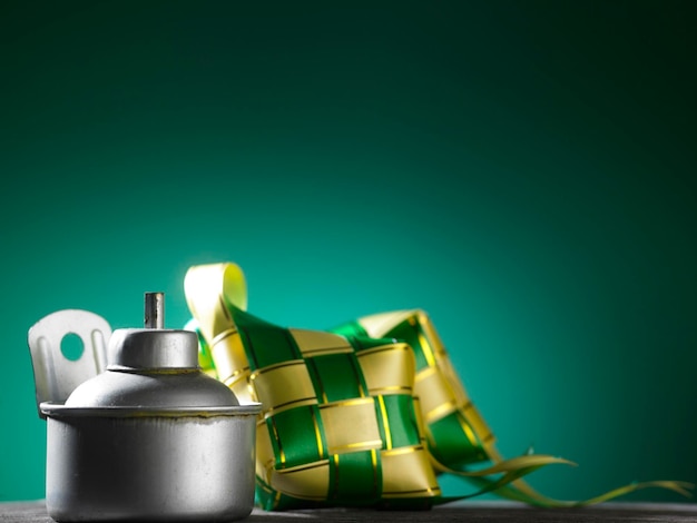 Photo close-up of oil lamp and ketupat  on green color background
