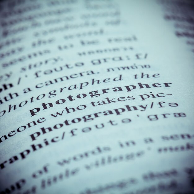 Close up of old English dictionary page with word Photographer. 