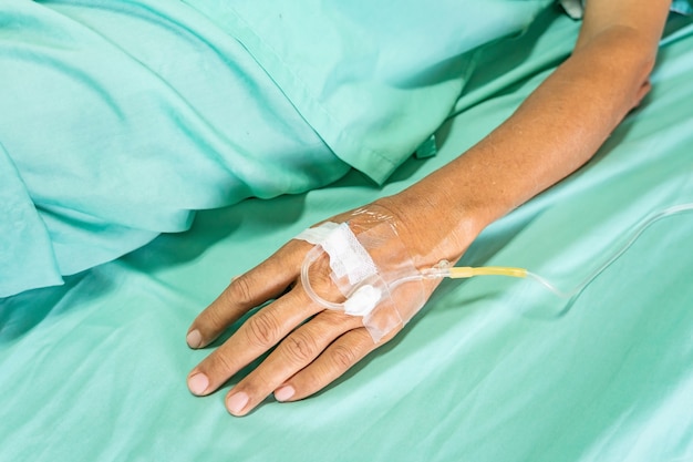 Foto chiuda in su del paziente anziano con flebo di infusione in ospedale.