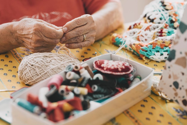 Close up of old mature woman hands working with crochet and sewing thread Elderly indoor home leisure activity concept lifestyle Unrecognizable senior female people in hobby active life Aging youth