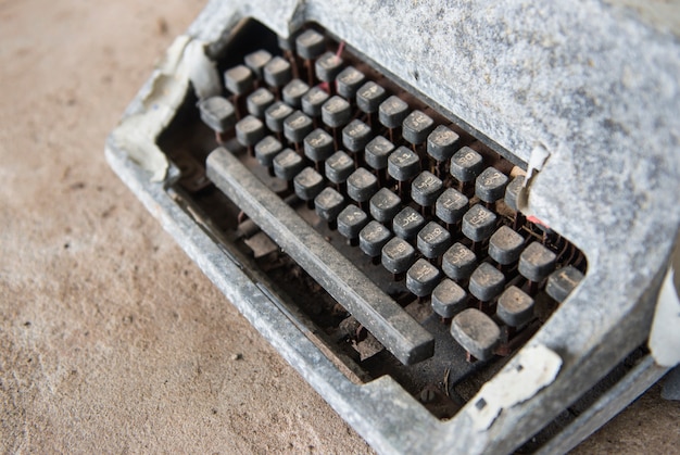 CLose up old typewriter. Part of rustic typewriter onconcrete floor.