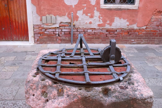 Close up old water well with iron grille in Italy Street scene old wall