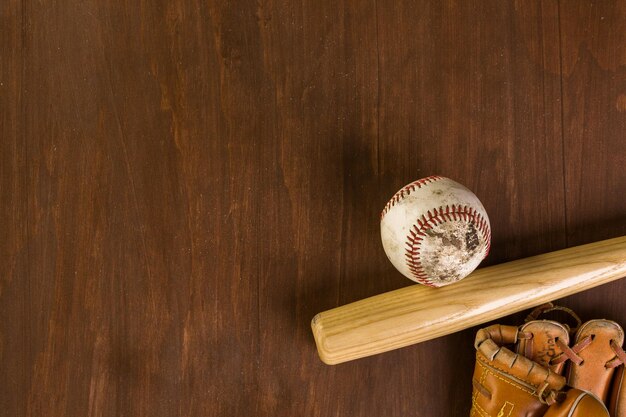 Chiuda in su della vecchia attrezzatura da baseball usurata su uno sfondo di legno.