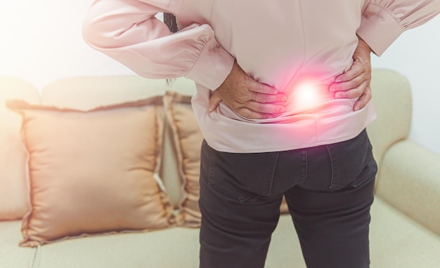 Close up older woman suffering from backpain health problem and\
people concept